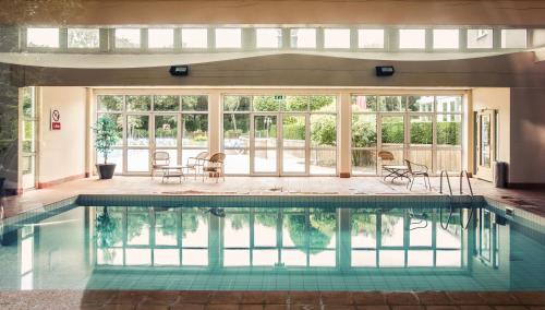 an indoor pool with chairs and tables and windows at Hotel De Zeeuwse Stromen in Renesse