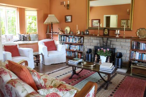 una sala de estar con chimenea y muebles blancos. en Klein Bosheuwel Guest House, en Ciudad del Cabo