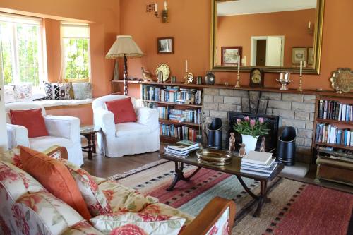 a living room with a fireplace and white furniture at Klein Bosheuwel Guest House in Cape Town