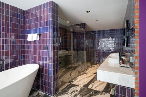 a bathroom with purple tiles and a tub and a sink at Santisookmidtown Pattani in Kampong Rusamileh