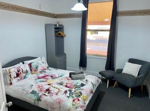 a bedroom with a bed and a chair and a window at Miners' cottage in Broken Hill