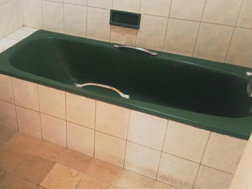 a green bath tub with a faucet in a bathroom at Hotel Wijaya Purwokerto in Purwokerto
