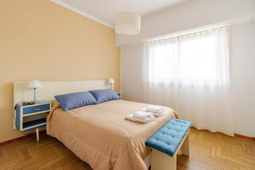 Un dormitorio con una cama con una silla azul y una ventana. en BAHÍA NORTE.Tres ambientes con cochera a metros del mar, en Mar del Plata