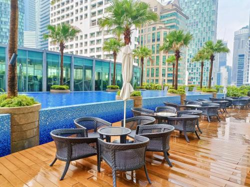 a hotel patio with tables and chairs and palm trees at Vortex Apartment Near By Klcc in Kuala Lumpur