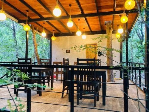 a restaurant with wooden tables and chairs and lights at Jungle Shades villa - Habarana in Habarana