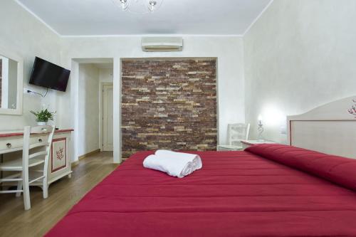 a red bed in a room with a brick wall at Morpheo Rooms in Alghero