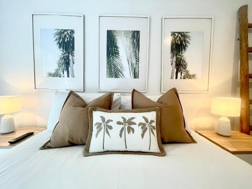 a bedroom with three pictures of palm trees on the wall at The Noosa Apartments in Noosa Heads