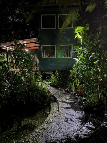 a green house with windows in a garden at night at Finca Tatin Hotel in Lámpara