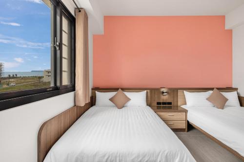 two beds in a room with a window at 西里海岸 電梯民宿 in Magong