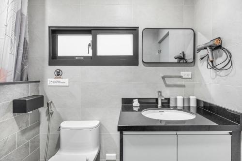 a bathroom with a sink and a toilet and a mirror at 西里海岸 電梯民宿 in Magong