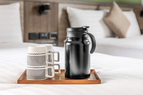 a black thermos on a wooden tray on a bed at 西里海岸 電梯民宿 in Magong