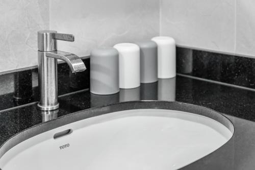 a sink with a faucet and four white candles at 西里海岸 電梯民宿 in Magong