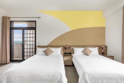 two white beds in a room with a window at 西里海岸 電梯民宿 in Magong
