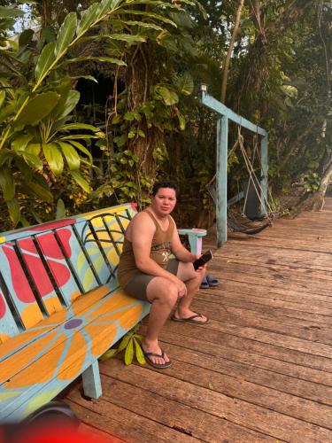 a man sitting on a bench on a boardwalk at Finca Tatin Hotel in Lámpara