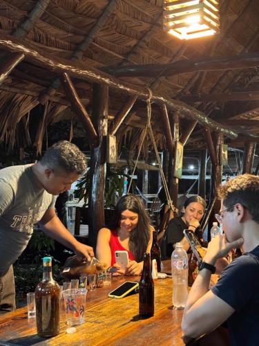 a group of people sitting around a wooden bar at Finca Tatin Hotel in Lámpara