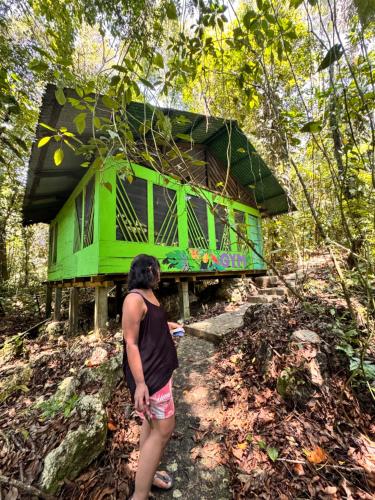 a woman standing in front of a green house at Finca Tatin Hotel in Lámpara