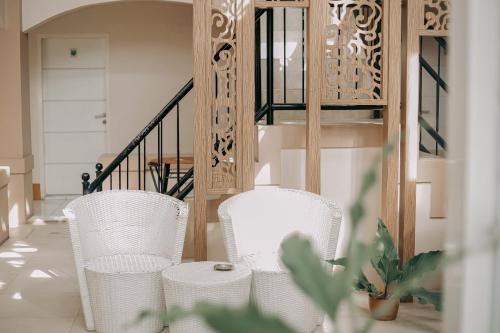 two white chairs in a room with a staircase at RedDoorz at Tienery Guest House in Tanjungkarang