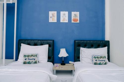 two beds in a room with blue walls at RedDoorz at Tienery Guest House in Tanjungkarang