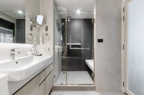 a bathroom with a shower and a sink and a mirror at Bayphere Hotel Pattaya JC in Na Jomtien