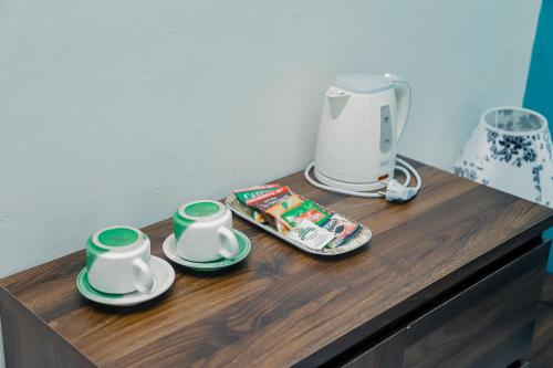 a counter with two cups and a coffee maker on it at RedDoorz at Tienery Guest House in Tanjungkarang