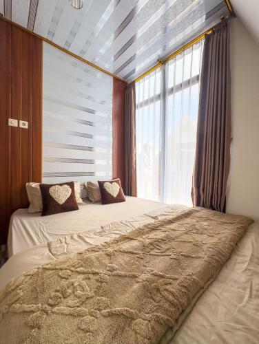 a bedroom with two beds and a large window at Homestay Begonia Syari'ah in Dieng