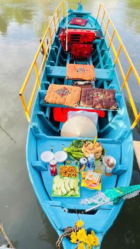 a blue boat in the water with food on it at HOMESTAY Hoàng GIa in Ấp Ông Tú