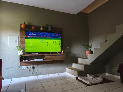 a living room with a television with a soccer game on it at Linda casa período Agrishow 2026 in Jaboticabal