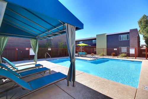 a swimming pool with two lounge chairs and a blue umbrella at 2 Bed 1 Bath Quiet Apartment Central Location in Phoenix in Phoenix