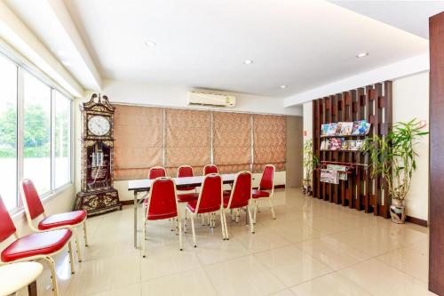 a dining room with red chairs and a table and a clock at Collection O VResotel in Nonthaburi