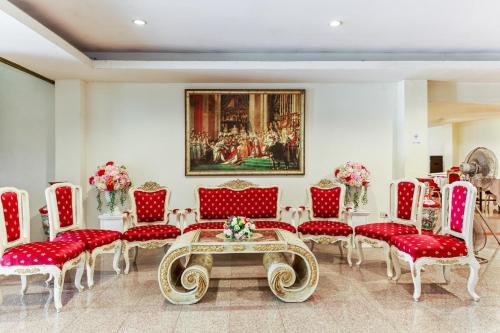 a room with red chairs and a table and a painting at Collection O VResotel in Nonthaburi