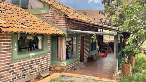 a brick house with a porch with a red hose at Xie-Hermosa cabaña con lago natural in Sáchica