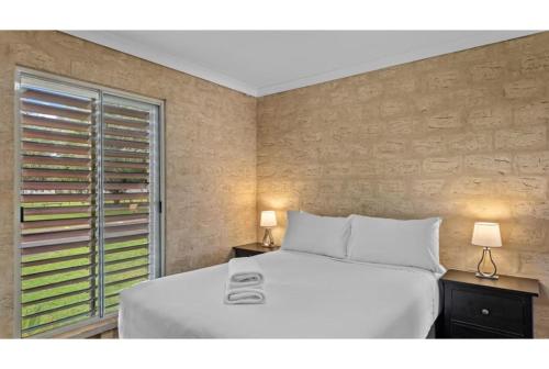 a bedroom with a white bed and a window at Discovery Parks - Bunbury Foreshore in Bunbury