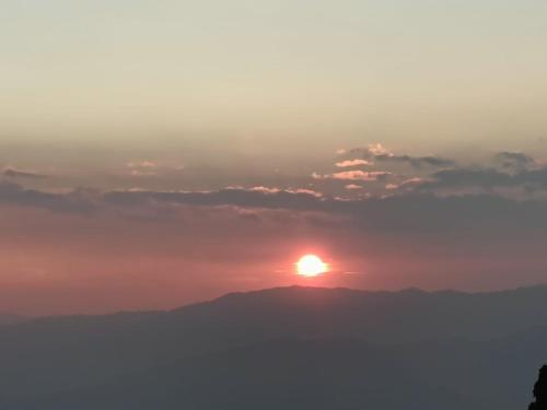 a sun setting on top of a mountain at Wangchan Homestay in Darjeeling