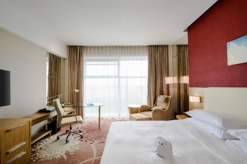 a hotel room with a bed and a desk at Four Points by Sheraton Qingdao, Chengyang in Qingdao