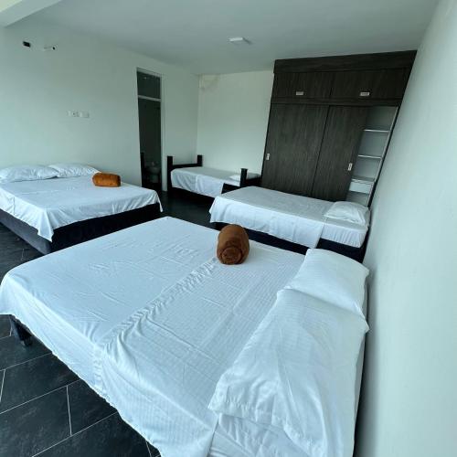 a room with three beds with white sheets and aigilinylinylinylinylinyl at XDfinca in Palermo