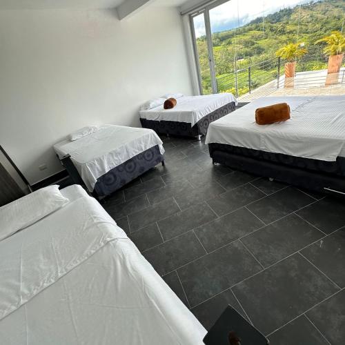 three beds in a room with a large window at XDfinca in Palermo