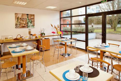 - une salle à manger avec des tables, des chaises et des fenêtres dans l'établissement Séjours & Affaires Genève Saint Genis, à Saint-Genis-Pouilly