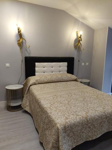 a bedroom with a bed with two lights on the wall at Lugomar-Feijoo in Alpedrete