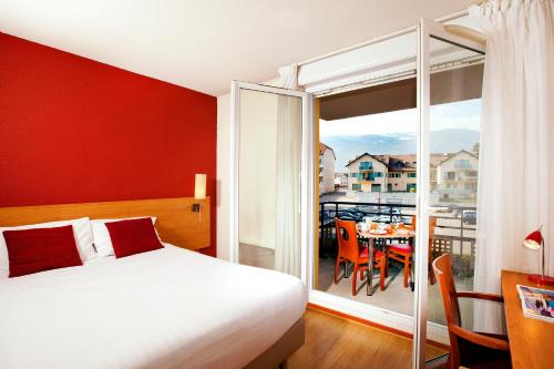 een slaapkamer met een bed en een balkon met een tafel bij Séjours & Affaires Genève Saint Genis in Saint-Genis-Pouilly