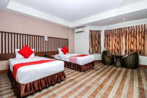 two beds in a hotel room with red pillows at Collection O JA Siam City in Pattaya