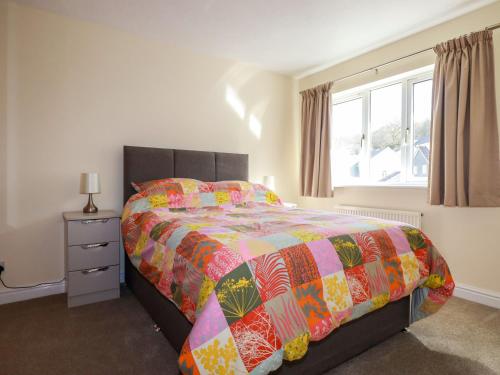 una camera da letto con un letto con un piumone colorato e una finestra di 12 Kel Avon a Truro
