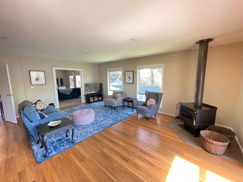 a living room with a blue couch and a wood stove at Cassini in Venus Bay