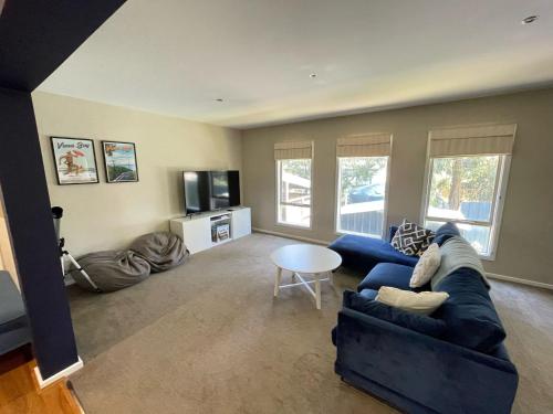 a living room with a blue couch and a table at Cassini in Venus Bay