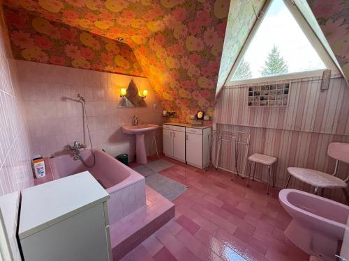 La salle de bains est pourvue d'une baignoire rose et d'un lavabo. dans l'établissement Maison de caractère dans le Vercors, 7 pers, 4 ch, wifi et grand jardin - FR-1-737-96, à Méaudre