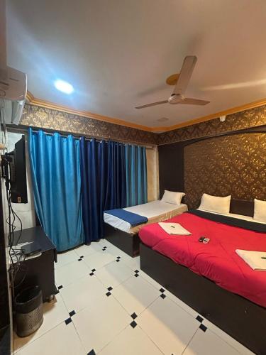a bedroom with two beds and a tv and blue curtains at Hotel Horizon Lonavala in Lonavala