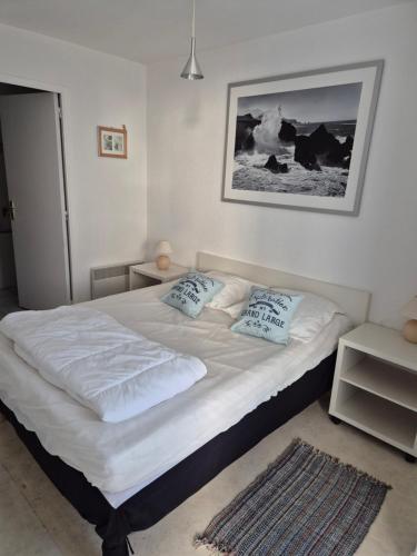 une chambre avec un lit avec des draps blancs et des oreillers dans l'établissement Macareux, à Perros-Guirec