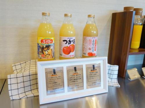 Três garrafas de suco de laranja em cima de uma bancada. em APA Hotel Honhachinohe em Hachinohe