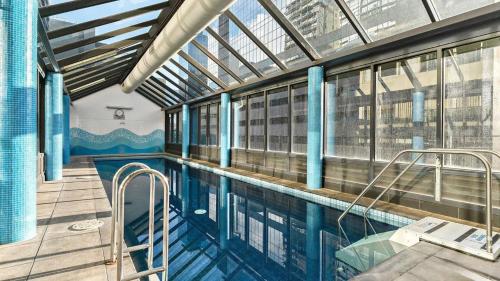 a swimming pool in a building with a large window at Stylish Cosy Gem w Pool, Tennis Court, & Parking in Melbourne