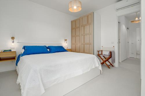 a white bedroom with a large bed with blue pillows at Casa Dina in Golfo Aranci