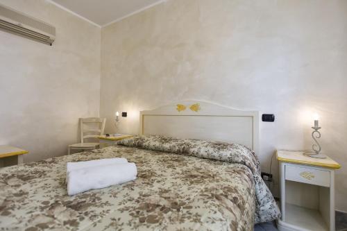 a bedroom with a bed and two tables and a chair at Morpheo Rooms in Alghero